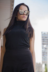 Young woman wearing sunglasses while standing against sky