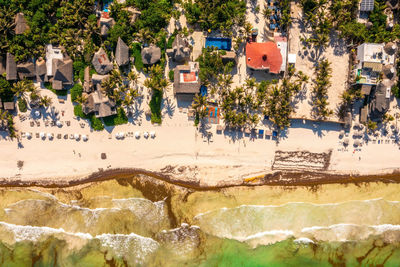 Aerial tulum coastline by the beach with a magical caribbean sea and small huts by the coast.