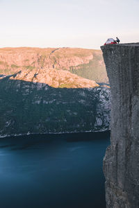 Scenic view of mountain and lake with man on rock against sky