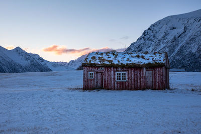 House on snow covered landscape against sky