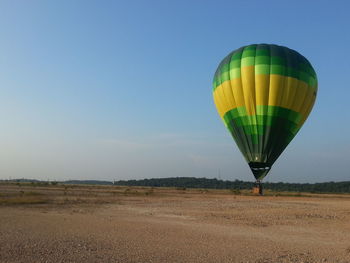 Hot air balloon on landscape against clear blue sky