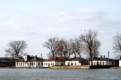 Houses by river and buildings against sky