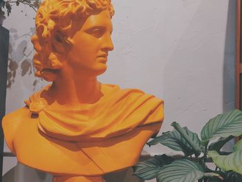 Close-up of yellow statue against wall