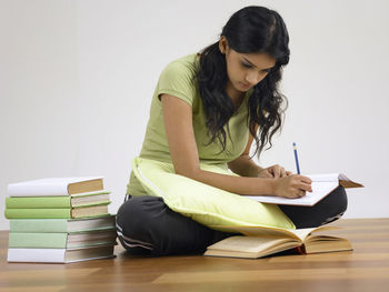 Young woman studying on hardwood floor at home