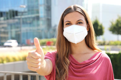 Portrait of young woman wearing flu mask holding file walking on road