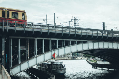 Suspension bridge in city against sky