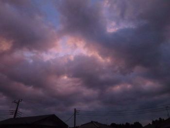 Low angle view of silhouette electricity pylon against dramatic sky