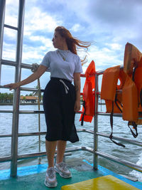 Woman standing by railing against sky