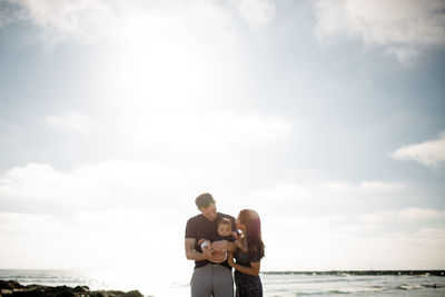 Parents standing on jetty holding infant son