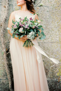 Midsection of bride holding bouquet