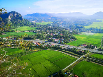 High angle view of agricultural field by buildings against sky