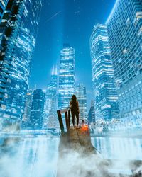 Rear view of man standing by illuminated buildings in city