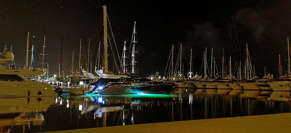 Sailboats moored at harbor against sky at night