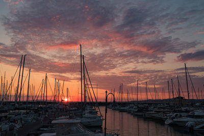 Sailboats moored at harbor during sunset