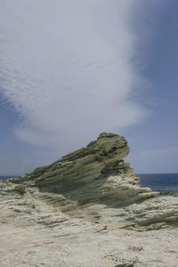 Rock formation on beach against sky