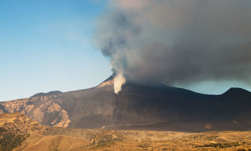 Smoke emitting from volcanic mountain against sky