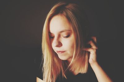 Close-up of thoughtful woman against black background