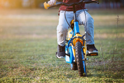 Low section of boy riding bicycle on grass