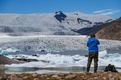 Rear view of man photographing snowcapped mountain at jokulsarlon glacial lagoon