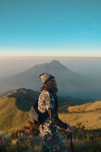 Rear view of man looking at mountain range against sky