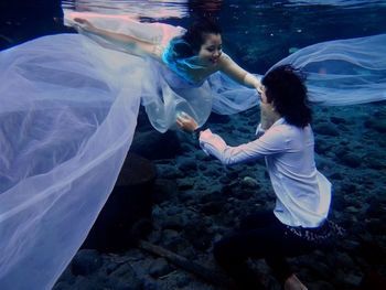 Bride and groom swimming in sea