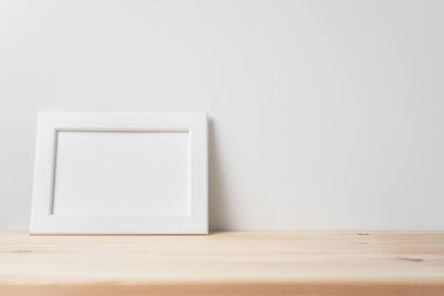 Close-up of empty table against white wall