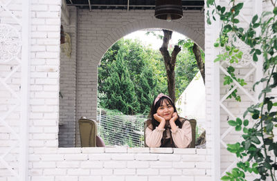 Portrait of woman sitting against plants