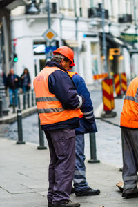 Rear view of men standing on street in city