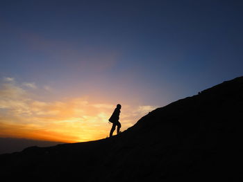 Silhouette person standing on mountain against sky during sunset