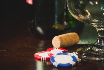 Close-up of gambling chips by wine bottle on table at casino