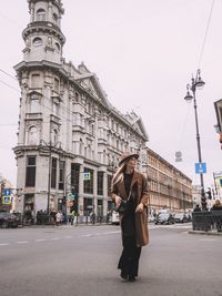 Woman walking on road against clear sky in city