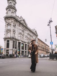 Woman standing on road against sky in city