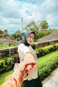 Portrait of young woman standing against trees