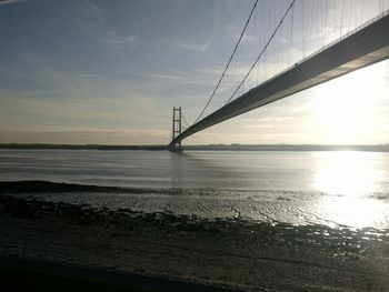 Suspension bridge over sea against sky