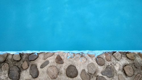 Wall by swimming pool against blue sky