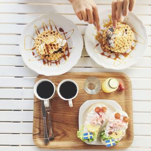 Cropped image of hands cutting waffles in plate on table