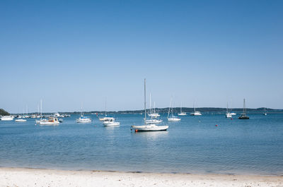 Boats in sea against clear sky