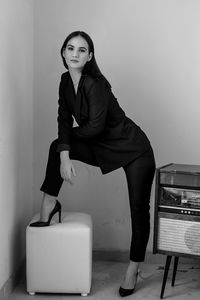 Portrait of woman standing by vintage record player against wall