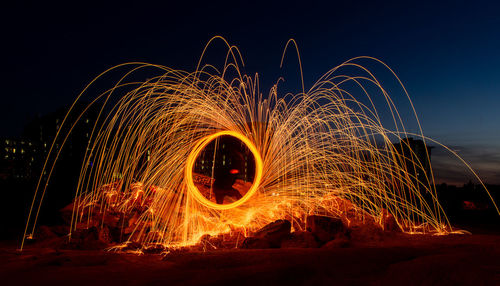 Illuminated firework display against sky at night