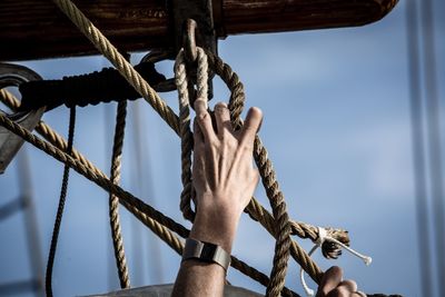 Low angle view of man holding tied rope on boat