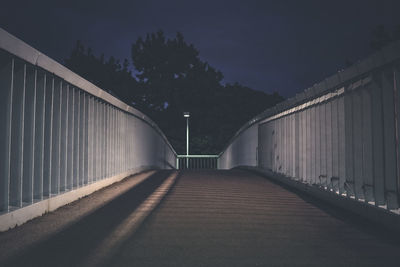 Empty footbridge against sky at night