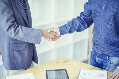 Midsection of business people shaking hands at office