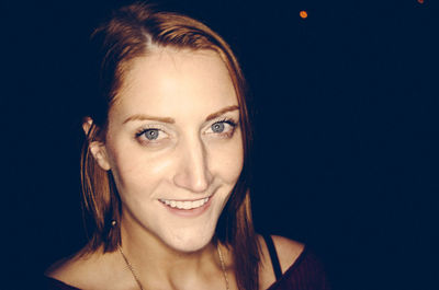 Portrait of young woman over black background