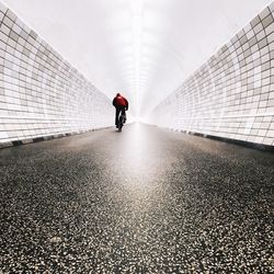 Rear view of man riding bicycle in tunnel