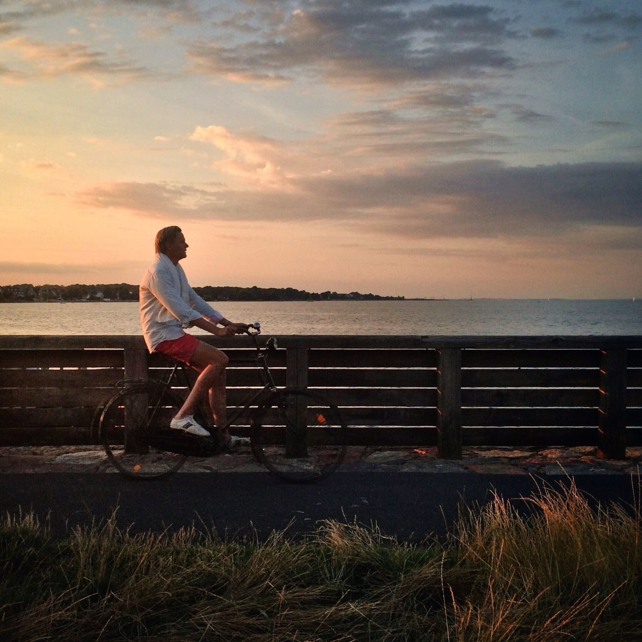 full length, rear view, sky, lifestyles, standing, casual clothing, leisure activity, cloud - sky, men, railing, water, side view, nature, sitting, person, tranquility, cloud, bench