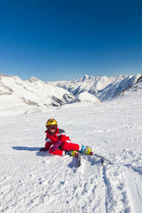 Girl skier sitting and resting on a ski slope in high mountains