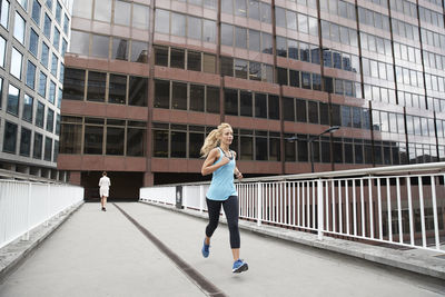 Full length of woman running against buildings in city