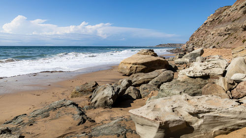 Rock formation on beach against sky