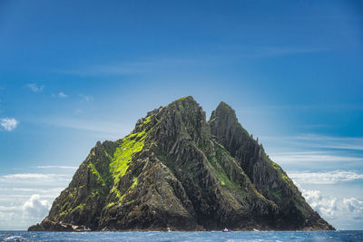 Rock formation in sea against blue sky