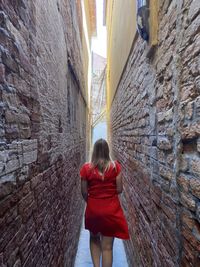 Rear view of woman standing by wall
